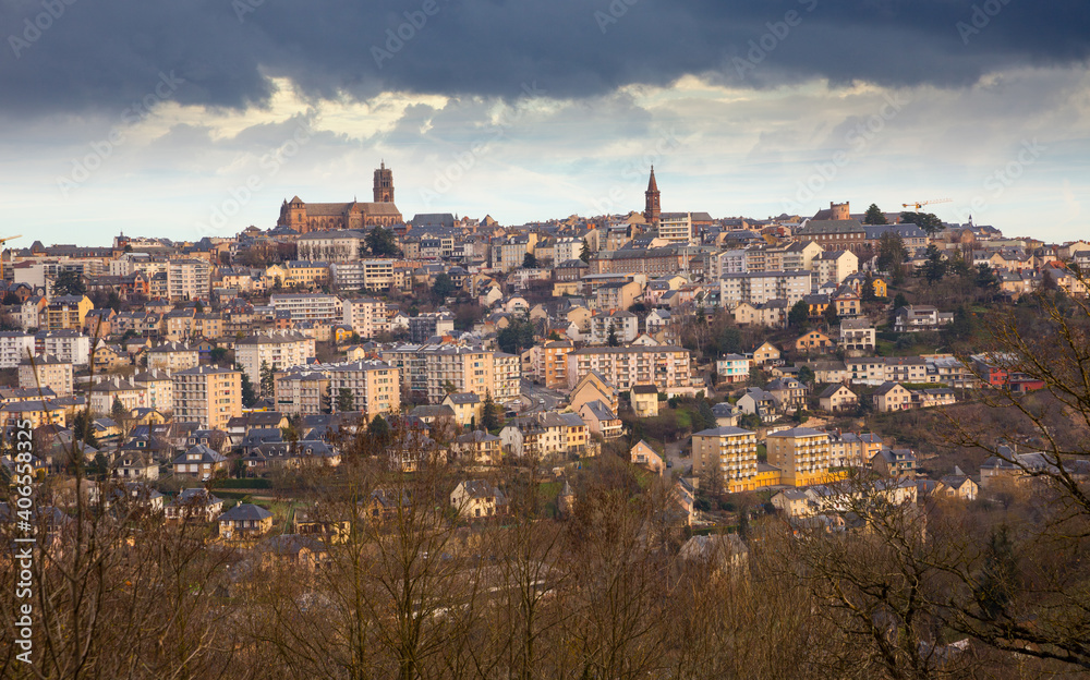 Fototapeta premium Panoramic view of French city of Rodez with tower of Cathedral and spire of church of Saint Amans in cloudy winter day