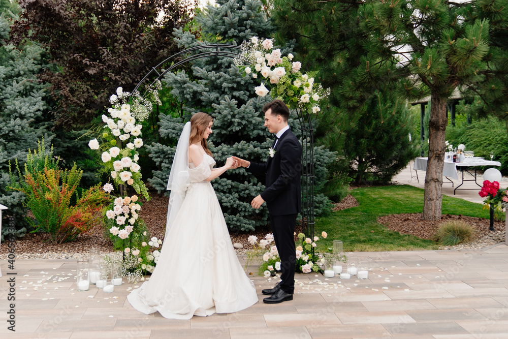 outdoor wedding ceremony in an arch of living flowers.newlyweds exchanged rings