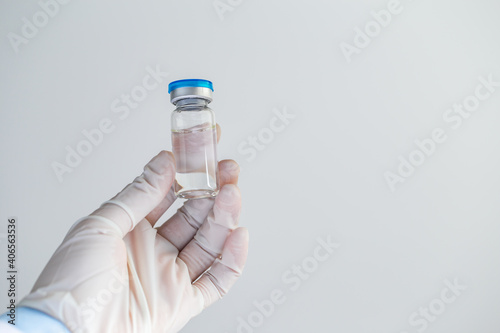 Doctor or scientist holding ampoule liquid vaccines with medication in the laboratory. Vaccination and immunization. Close up.