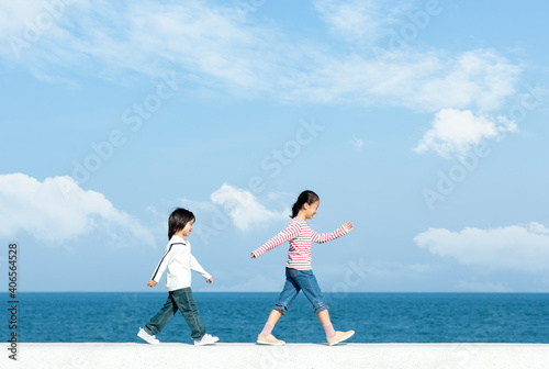 Fotobehang 防波堤を歩く女の子と男の子