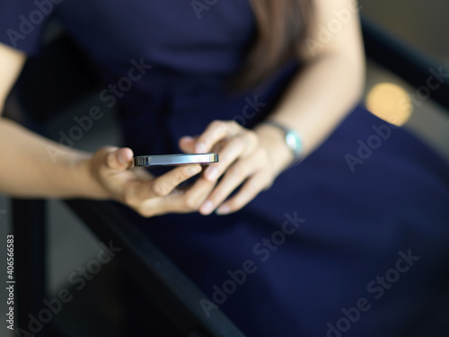 Female hands using smartphone while sitting on the chair in office room