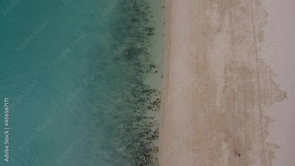 Drone flying up over a tropical white sand beach with calm waves and people walking. Drone flying up over a tropical white sand beach with calm waves and people walking.
