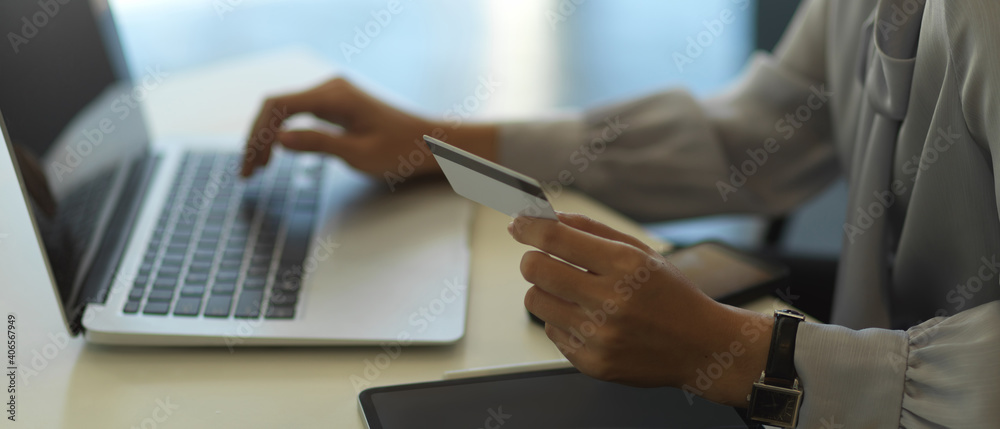 Female hand holding credit card while online paying on laptop Female hand holding credit card while online paying on laptop