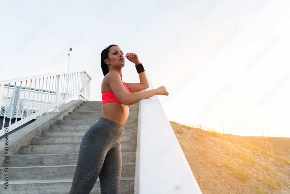 Attractive dark hair girl in stretchy pants resting after running enjoying the sunset