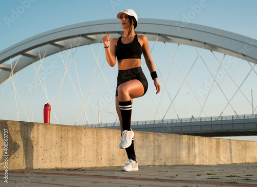 Female runner, athlete, tanned and fit, warming up outdoors before exercises or run  © phoenix021