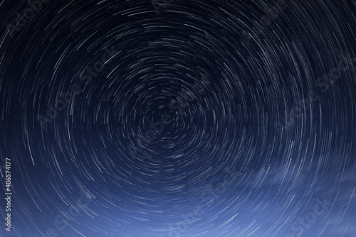 Stellar trails, the rotation of bright stars at night around the Polar Star against a blue sky