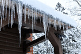 Icicles hanging off log cabin roof from melting snow after storm