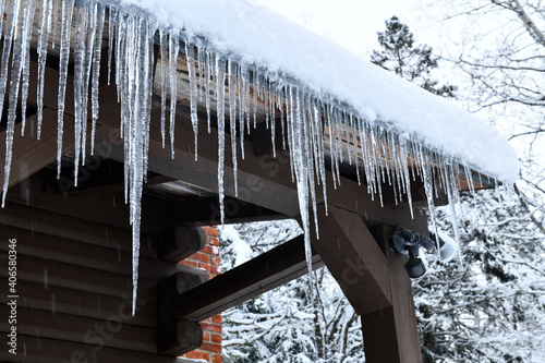 Fotografía Icicles hanging off log cabin roof from melting snow after storm