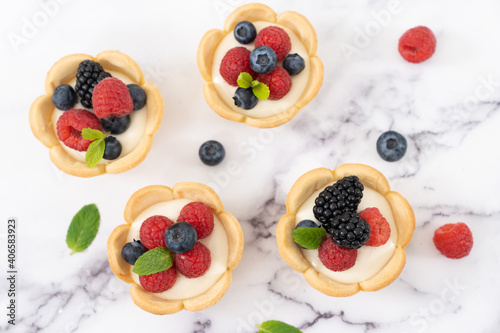 Delicious pastry mini fruit cream cheese pies or tart cakes with fresh raspberry  blueberry and blackberry