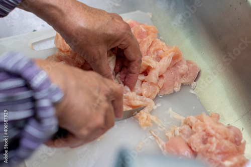 person cutting chicken meat