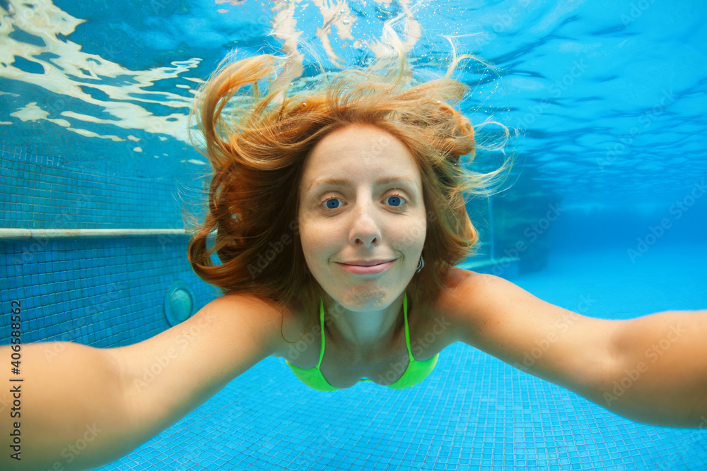 Funny portrait of teenager girl. Swim, dive in blue pool with fun