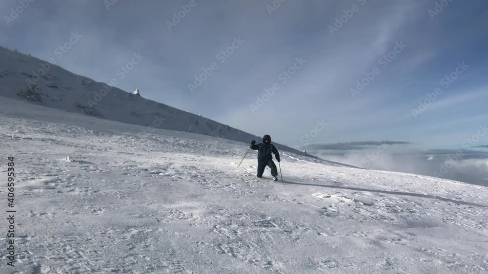 A young man is running through deep snow. He is running off the mountain. He is helping himself with trekking sticks. Mount Pikui. A young man is running through deep snow. He is running off the mountain. He is helping himself with trekking sticks. Mount Pikui.