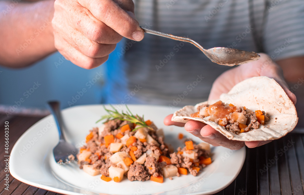 MAN EATING MEAT WITH VEGETABLES AND TORTILLA