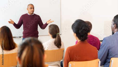 Hispanic lecturer is pointing something on board to his students