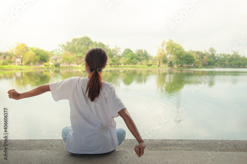 An Asian woman relaxing by the water in a park