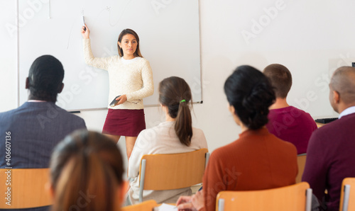 Female high school teacher standing in front of interactive whiteboard teaching lesson