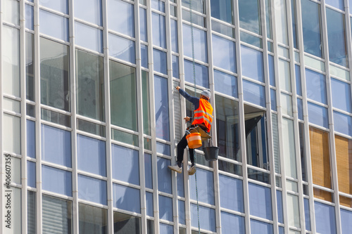 Outside of the building washing the glazing of the facade of a multi-storey building climbers clean windows.