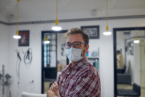 Hairdresser with surgical medical mask waiting for customers in a hair salon.