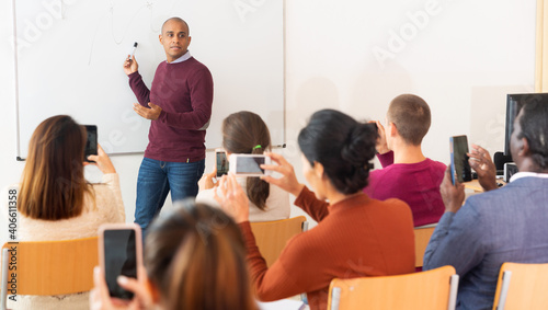 Multinational students with smartphones at business school doing videos of session