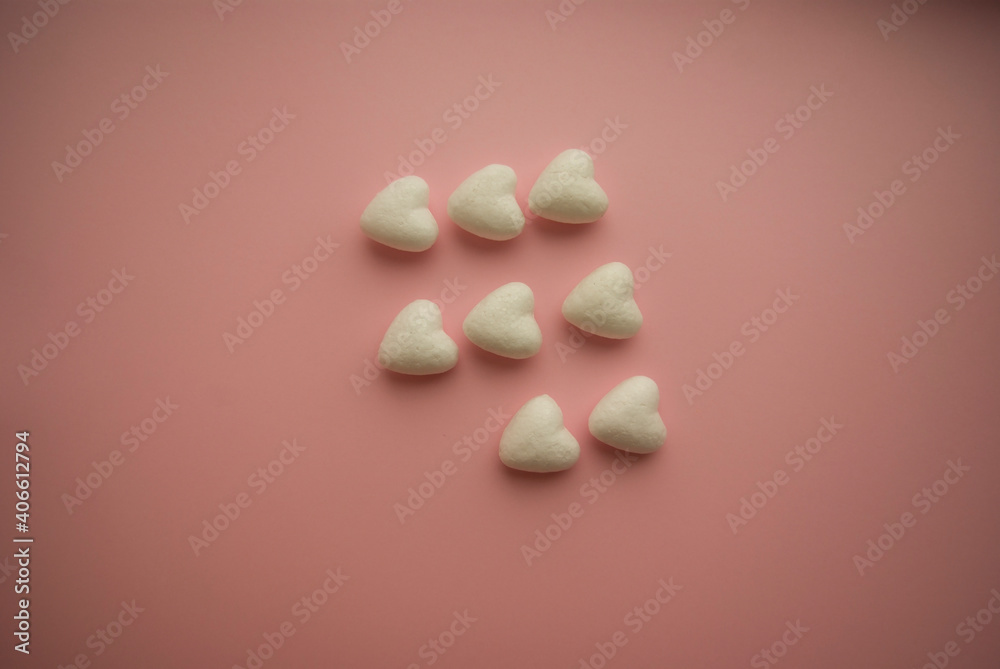 Small voluminous white hearts lie on a pink background in three rows and one heart is missing Small voluminous white hearts lie on a pink background in three rows and one heart is missing