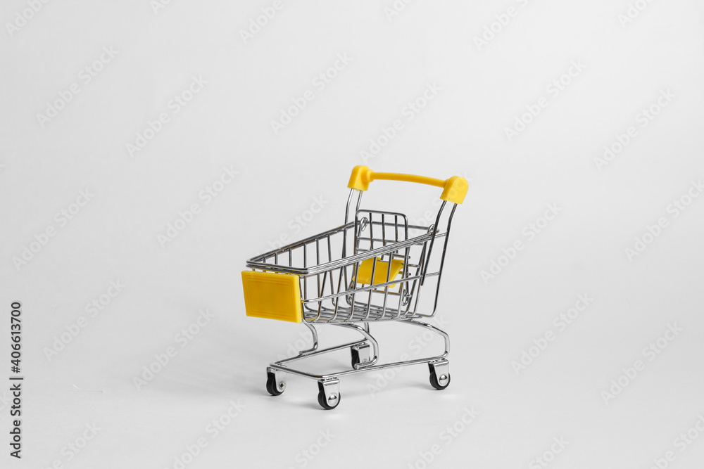 Empty miniature shopping cart placed on white background in studio for concept of purchases
