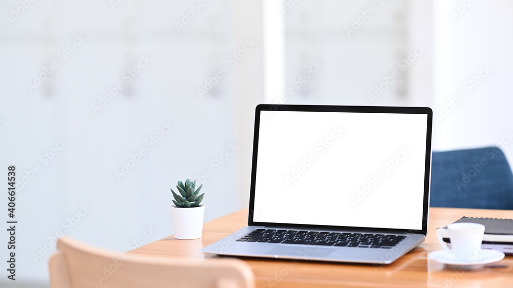 Fototapeta premium Minimal workplace with mock up laptop computer with white screen on wooden table.