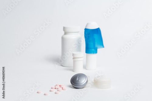 Contact lenses container and pile of pills placed against bottles with medicines and eye drops on white background in studio 