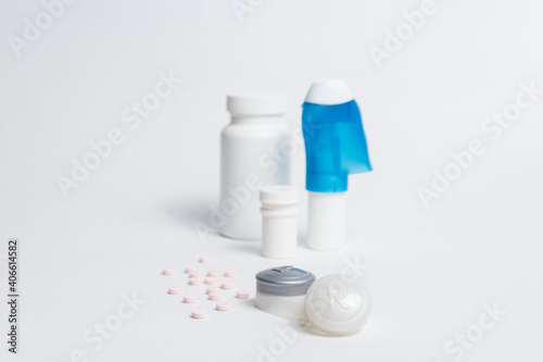 Eye drops bottle and contact lenses container placed on white background with pills in studio 