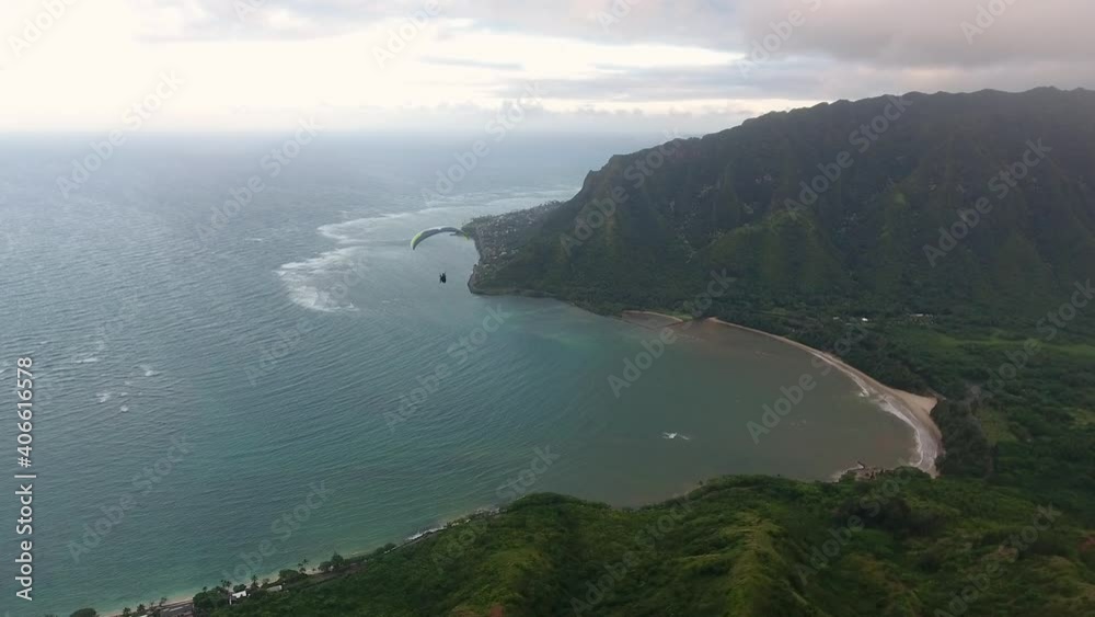 Paraglider flies along coast over hawaii, aerial drone Paraglider flies along coast over hawaii, aerial drone