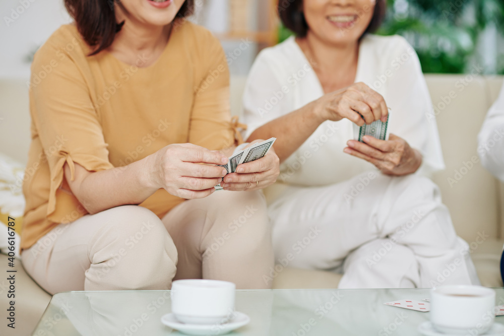 Group of smiling senior female friends playing cards at home and drinking coffee Group of smiling senior female friends playing cards at home and drinking coffee