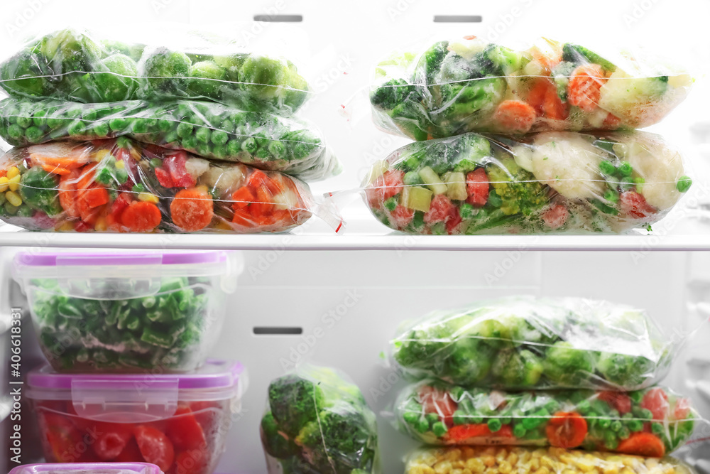 Containers and plastic bags with frozen vegetables in refrigerator Containers and plastic bags with frozen vegetables in refrigerator