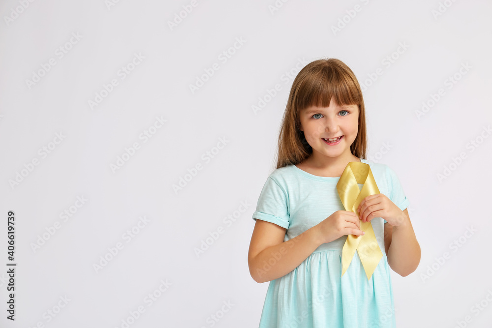 Little girl with golden ribbon on grey background. Childhood cancer awareness concept Little girl with golden ribbon on grey background. Childhood cancer awareness concept