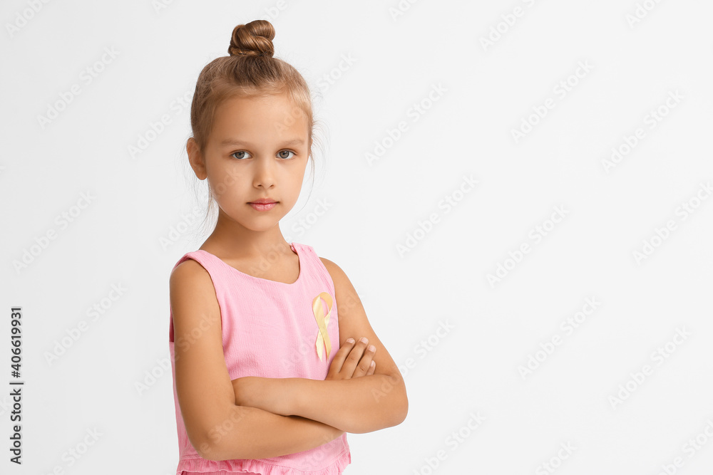 Little girl with golden ribbon on light background. Childhood cancer awareness concept Little girl with golden ribbon on light background. Childhood cancer awareness concept