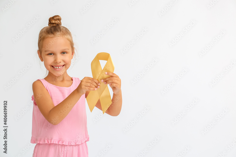 Little girl with golden ribbon on light background. Childhood cancer awareness concept Little girl with golden ribbon on light background. Childhood cancer awareness concept