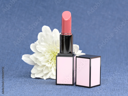 Matte nude lipstick in light pink rectangular square tube with white flower on blue background. Mock up, close up. Branding concept	