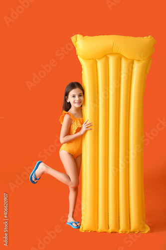 Cute little girl with inflatable mattress on color background