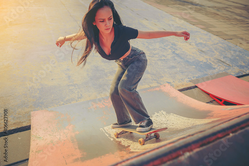 Young woman practising skateboarding at skate park. Women try to playing skateboard on the ramp.