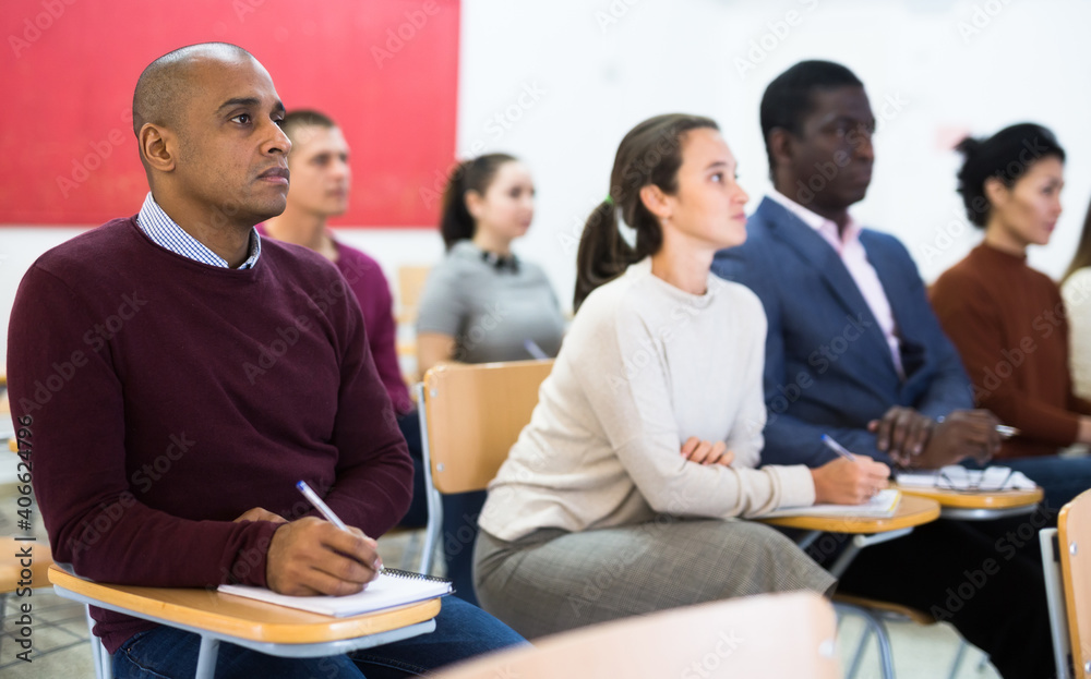 Fototapeta premium Multiethnic group of young people studying together at tables in classroom