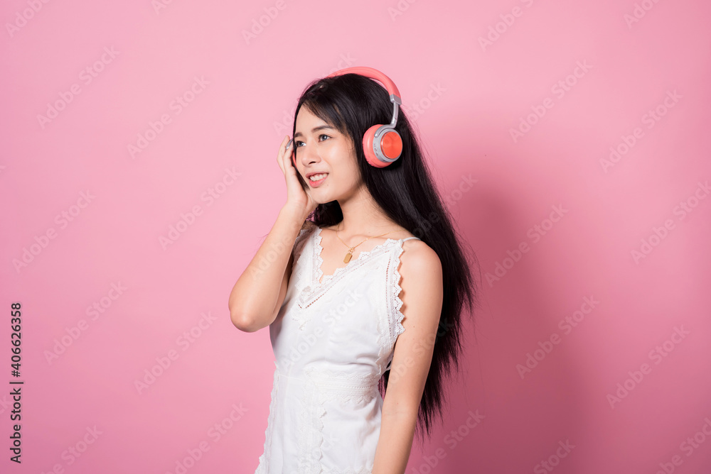 Happy smiling young asia woman with headphones enjoying listens to music over pink background Happy smiling young asia woman with headphones enjoying listens to music over pink background