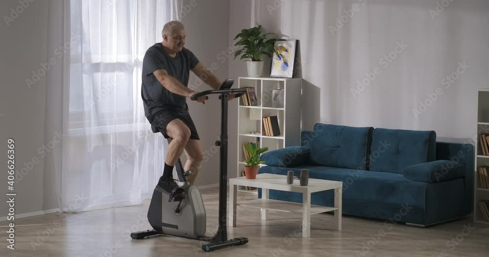 training on exercise bike for losing weight and keeping physical condition, middle aged man at home training on exercise bike for losing weight and keeping physical condition, middle aged man at home