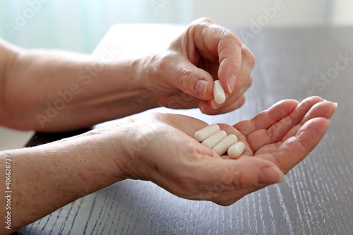 Elderly woman with pills in wrinkled hands. Medication in capsules, taking sedatives or vitamins