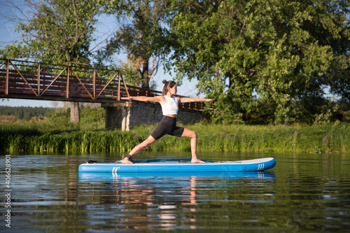 woman doing yoga on sup board at sunset. outdoor summer activity. Sup yoga.  Social Distancing. copy space. Mental Health
