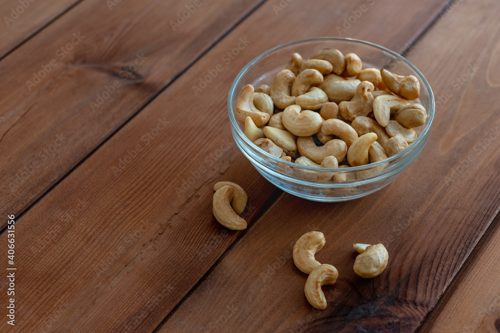 Bowl with roasted cashew nuts on wooden table. Vegetarian and healthy food concept Bowl with roasted cashew nuts on wooden table. Vegetarian and healthy food concept