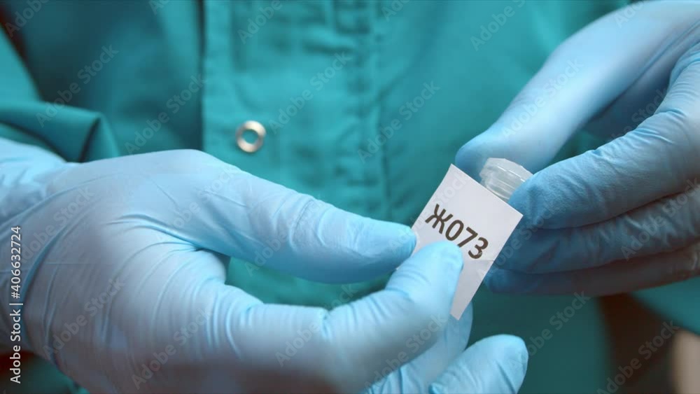 Man glues marker on tube with sample for coronavirus test Man glues marker on tube with sample for coronavirus test