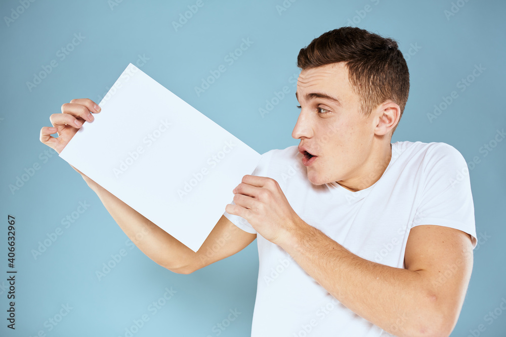 man holding a sheet of paper in his hands white t-shirt cropped view blue background man holding a sheet of paper in his hands white t-shirt cropped view blue background