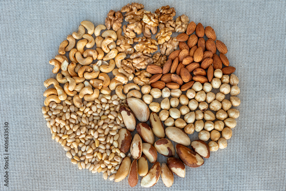 A circle of different nuts on linen fabrics, closeup. Nuts kernel of walnut, hazelnut, almond, brazil, cashew, pine nuts A circle of different nuts on linen fabrics, closeup. Nuts kernel of walnut, hazelnut, almond, brazil, cashew, pine nuts