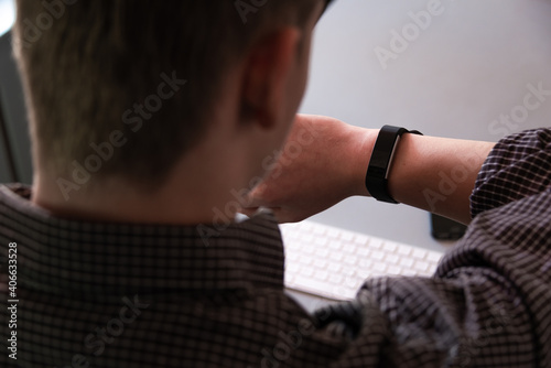 young man wearing smart watch ,seen from behind focus on watch . Business man at work or working from home . © robert