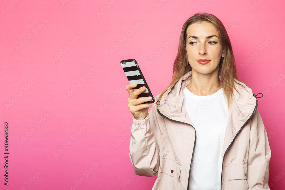 Young pensive woman holding phone, pink isolated background Young pensive woman holding phone, pink isolated background