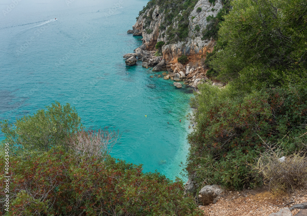 View over Gulf of Orosei with limestone cliffs, green bushes, white beach and turquoise blue water. Famous travel touristic destination in Sardinia island, Italy.