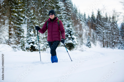 A woman practicing Nordic Walking in winter scenery. Active lifestyle of seniors. 